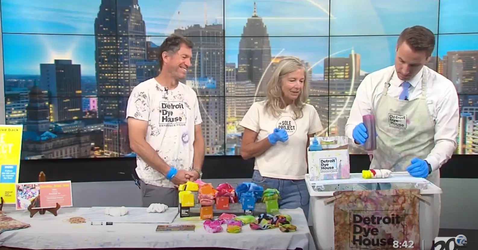 TV studio cooking segment with three people using Brightly Twisted tie dye clothing.