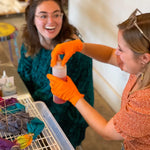 Two people in orange gloves collaborating at the Detroit Dye House during Dye Class 101