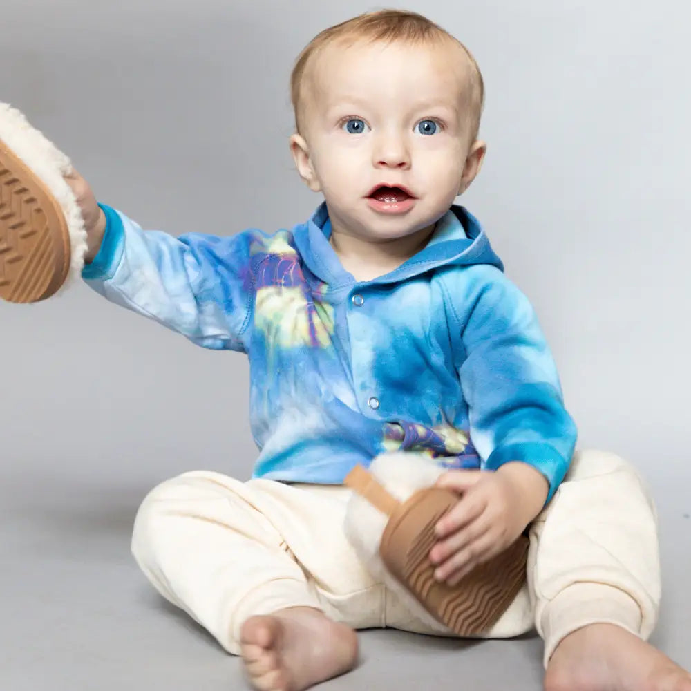 Baby in a tie dye blue hoodie and cream pants showcasing an adorable Kid Jacket