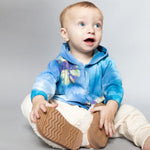 Baby in a tie dye blue hoodie and cream pants, modeling an adorable Kid Jacket