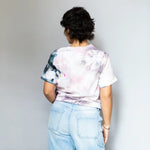 Person in DDH Tee with white tie-dye design and light blue jeans from behind