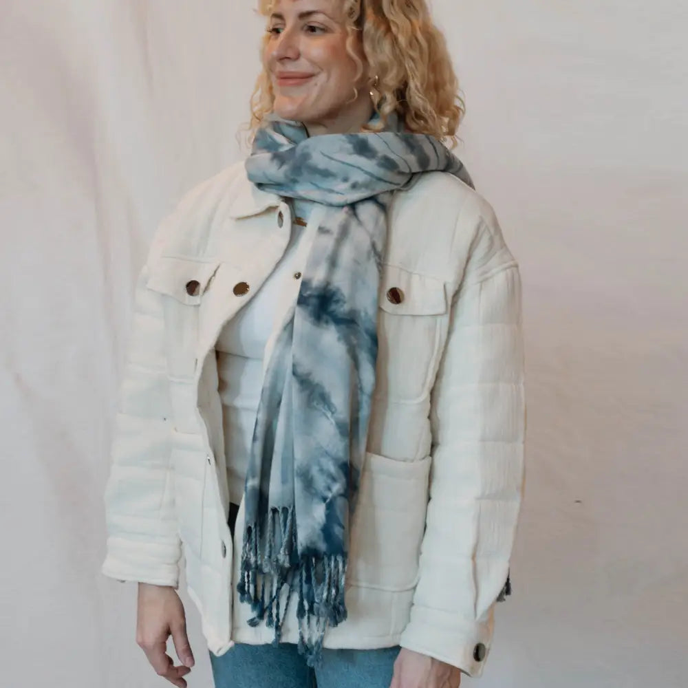 White denim jacket styled with a blue tie dye scarf for trendy clothing looks