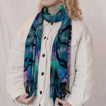 Colorful scarf with blue, turquoise, and purple tie dye patterns and black fringe