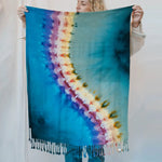 Tie-dyed shawl scarf with fringe and rainbow pattern on turquoise background