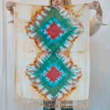 Tie-dye scarf in teal, red, and orange with diamond patterns and fringe accents