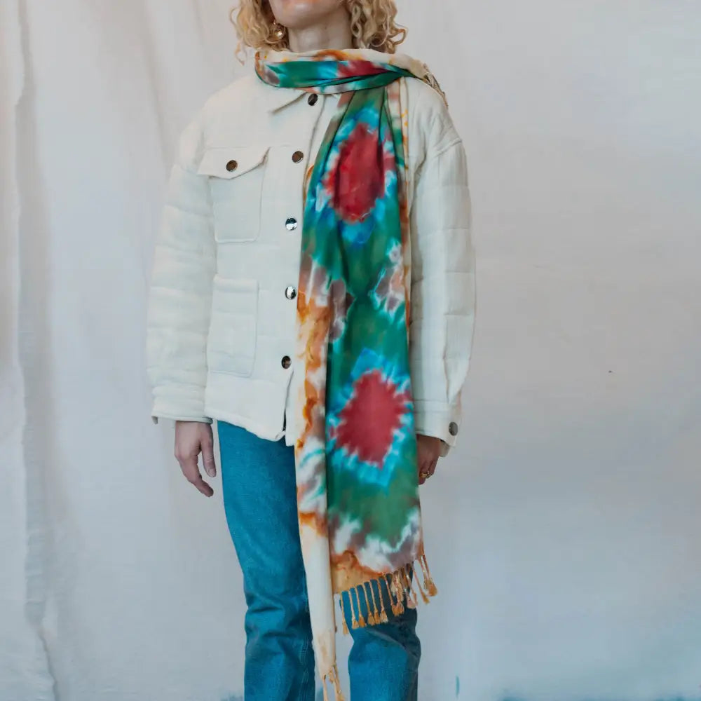 Colorful tie-dye scarf with fringe styled with a white jacket and blue pants