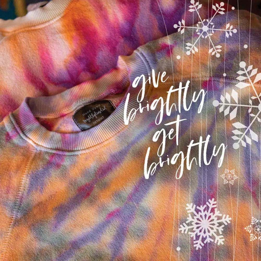 Tie-dyed sweatshirt with snowflakes and the phrase give brightly get brightly for gift card