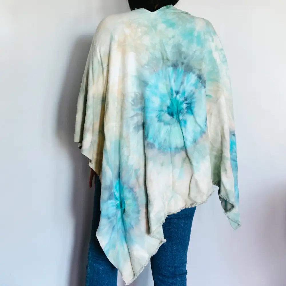 Tie dye wrap featuring turquoise spiral patterns on white fabric for trendy clothing