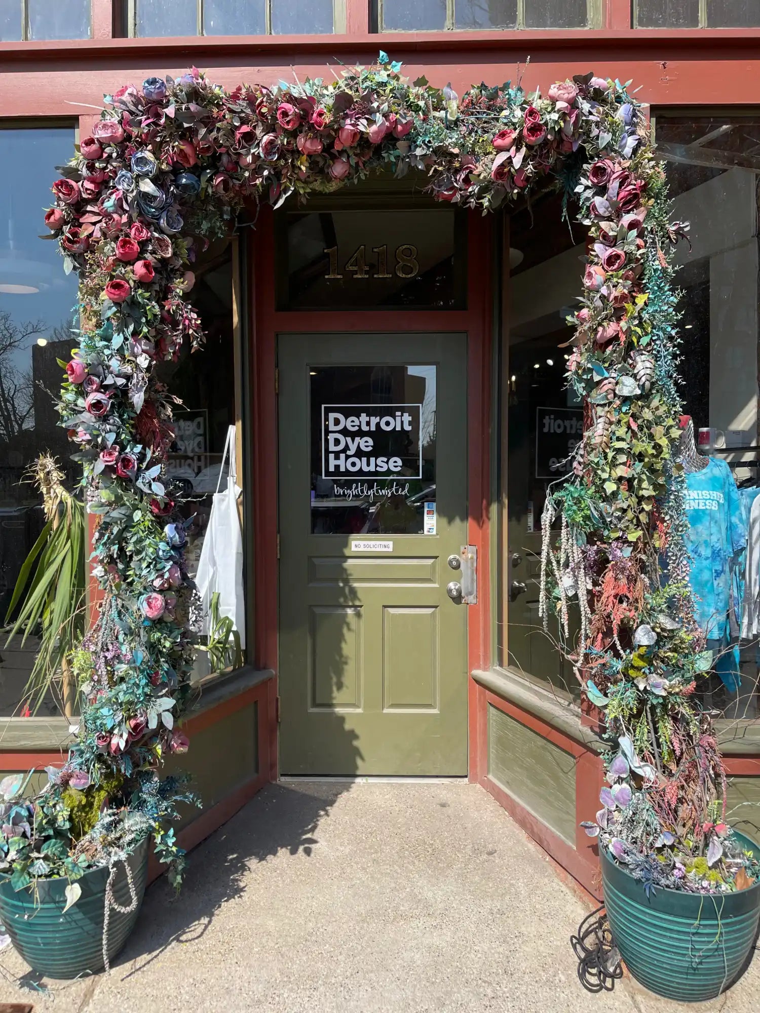 Floral-adorned doorway entrance to Detroit Dye House with a sage green door.