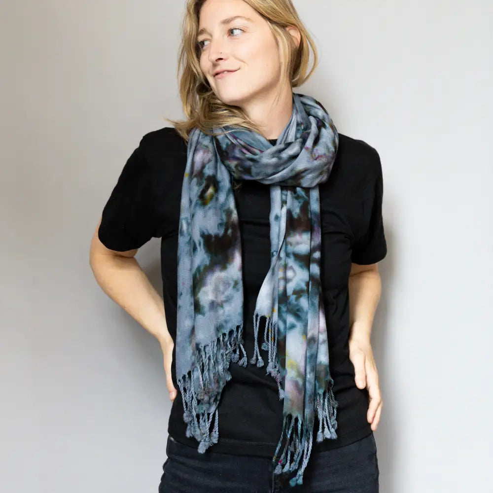 Tie-dyed blue and gray scarf wrapped around neck over black clothing for stylish warmth