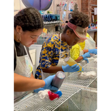 Two workers in gloves cleaning dishes at a CORKTOWN art studio for a birthday party