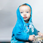 Baby in a bright blue kid jacket holding a disco ball, showcasing an adorable snap