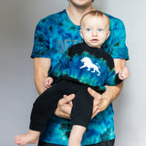 Parent and baby in matching tie dye blue dinosaur union suits clothing