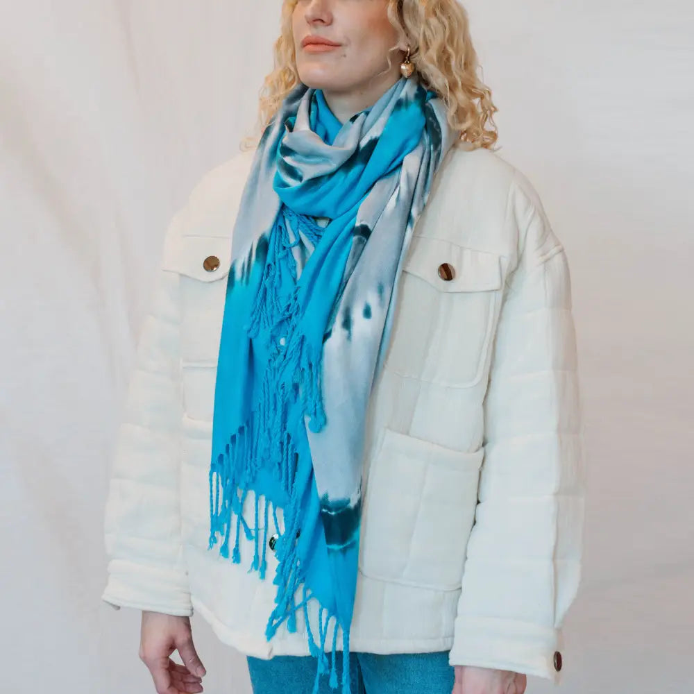 Bright turquoise scarf with fringe styled with a white jacket for fashionable clothing