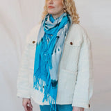 Bright turquoise scarf with fringe styled with a white jacket for fashionable clothing