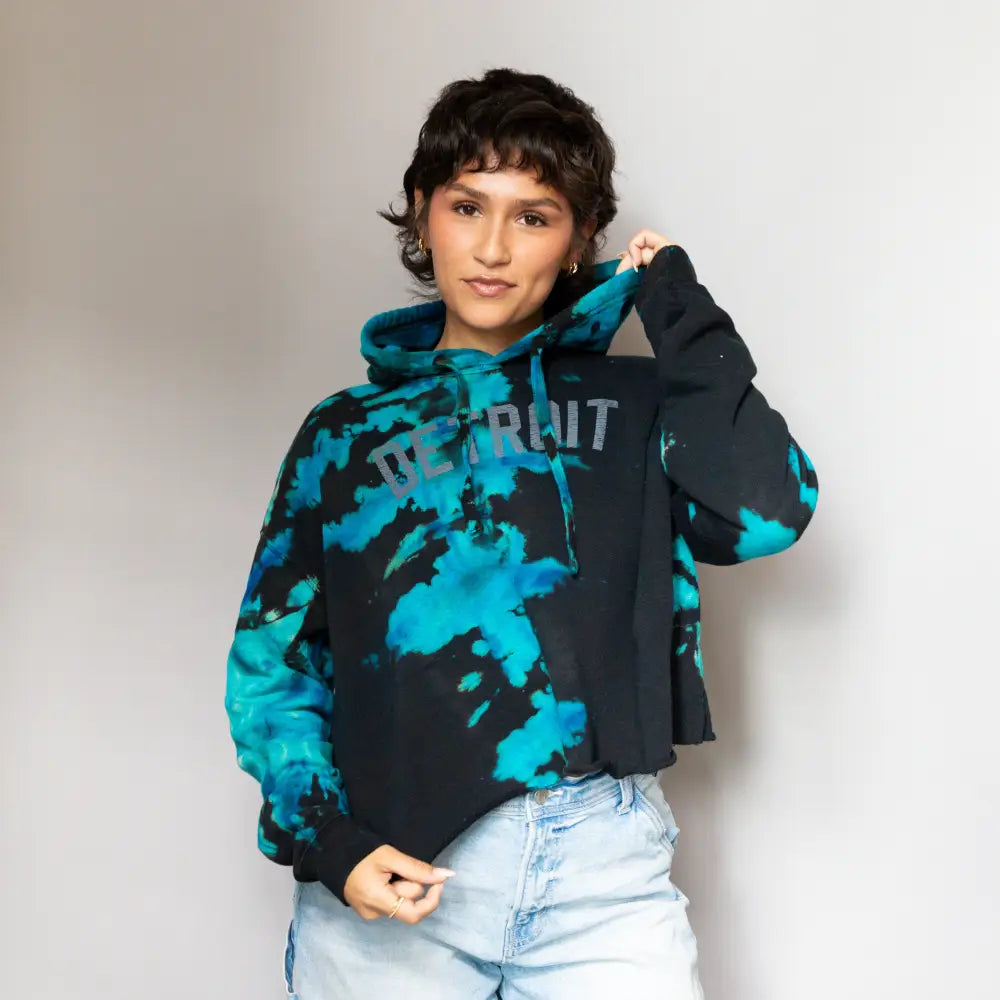 Tie-dye turquoise and black crop hoodie sweatshirt paired with light wash jeans