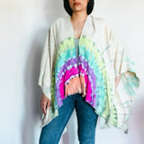 Tie dye kimono wrap with rainbow circular pattern worn over jeans for trendy clothing