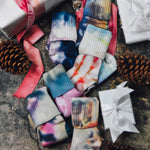 Super soft Tie-dyed socks with colorful patterns alongside pink ribbon and pinecones