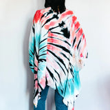 Tie-dyed poncho wrap in coral pink, turquoise blue, and black spiral pattern