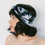 Tie-dyed blue and white BrightlyTwisted headband features worn with dark wavy hair