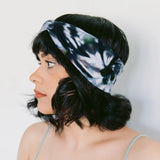 Tie-dyed blue and white BrightlyTwisted headband features worn with dark wavy hair