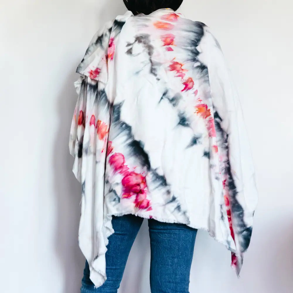 Tie dye wrap poncho in pink and gray patterns over blue jeans for stylish clothing